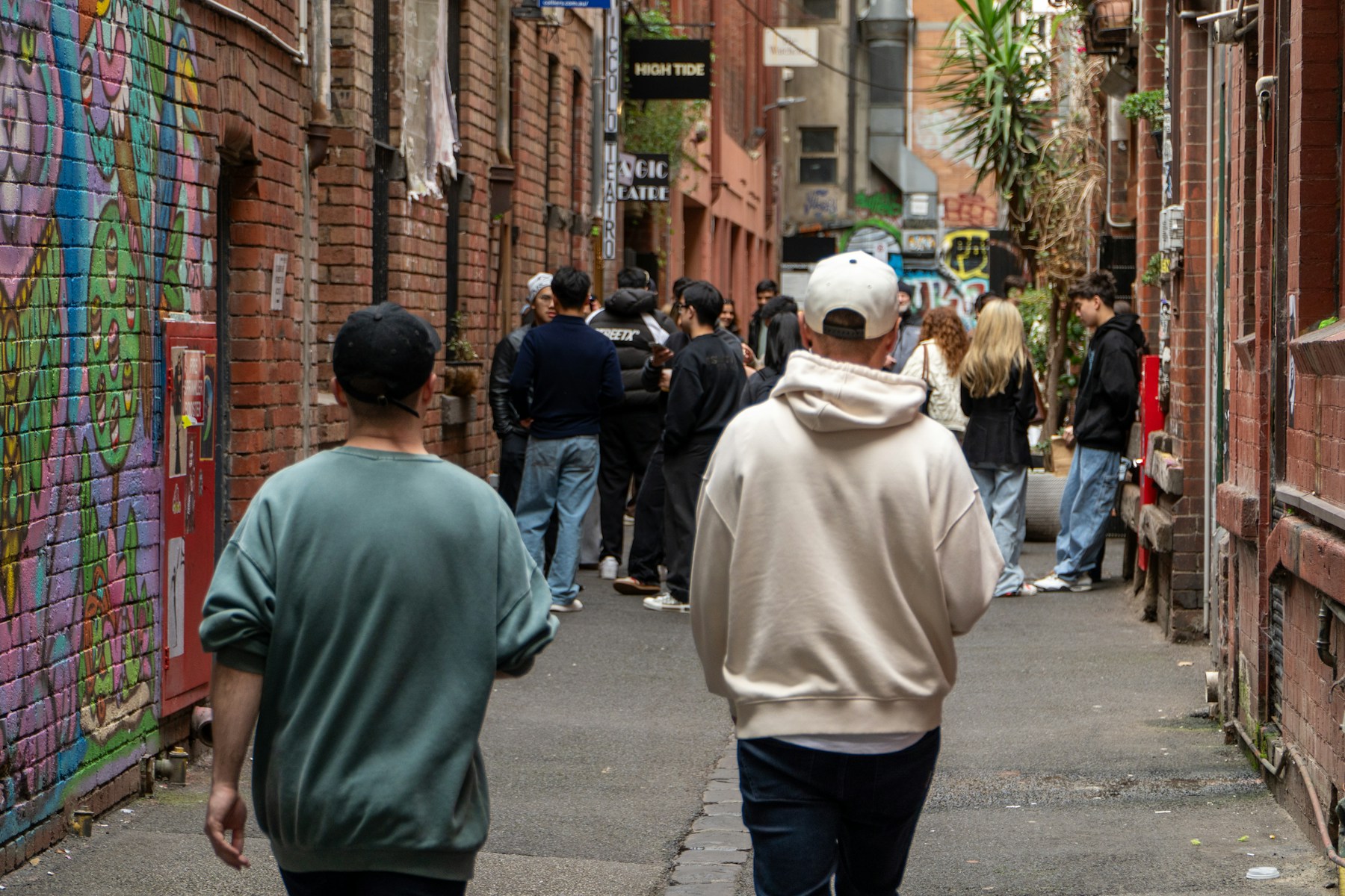 People walking through a graffitied city laneway